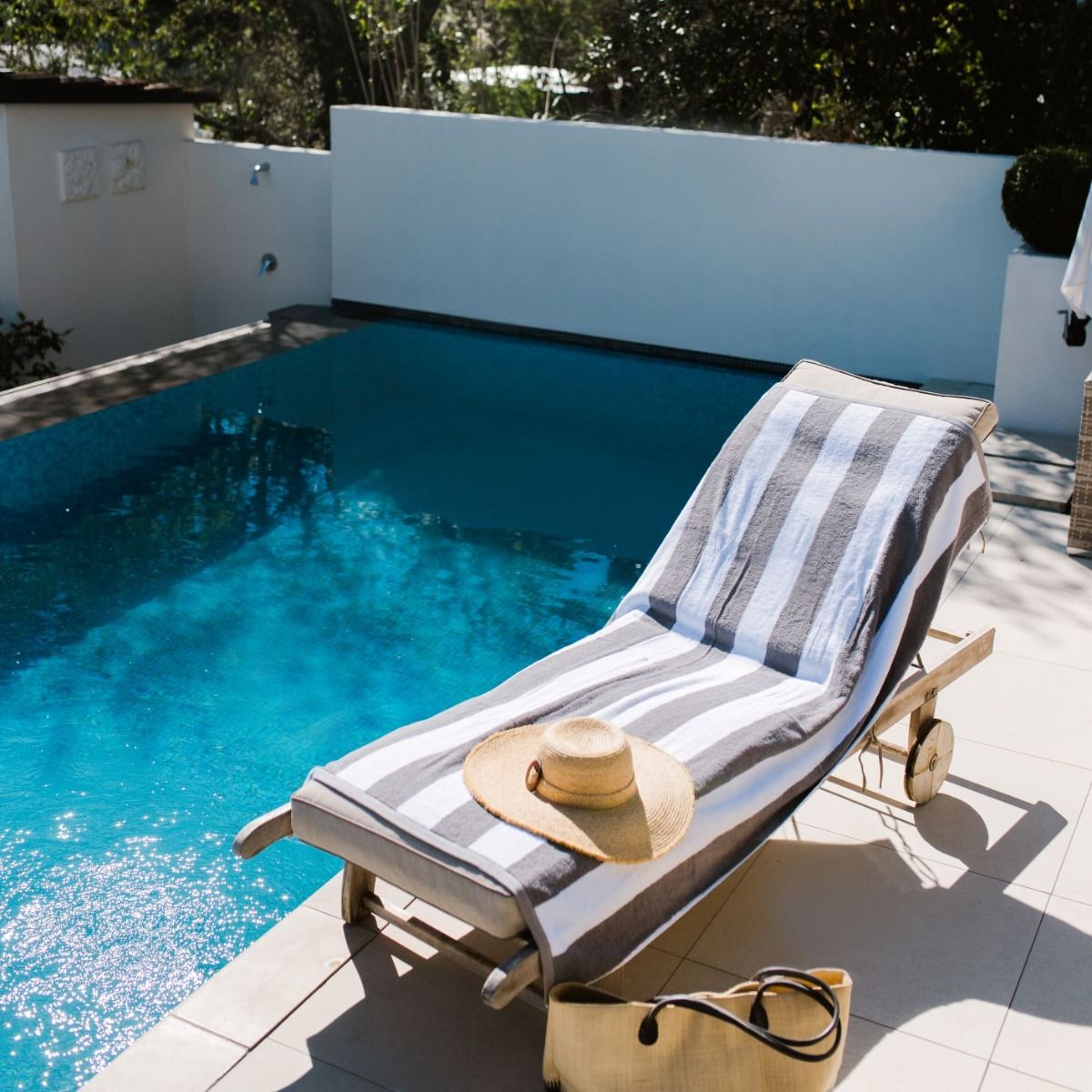 Cabana striped towel from Baksana in charcoal and white lying on a pool side deck chair