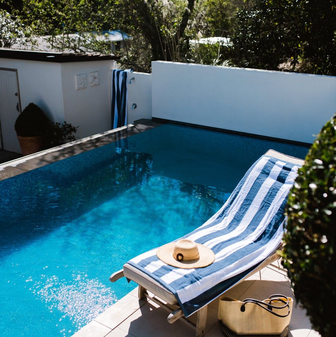 Cabana beach towel from Baksana in navy and white lying on a poolside lounger