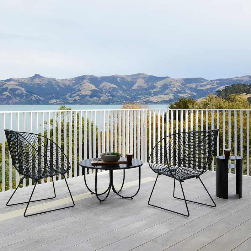 Coromandel wire chair with the Rotoiti outdoor table on a deck over looking mountains and a lake