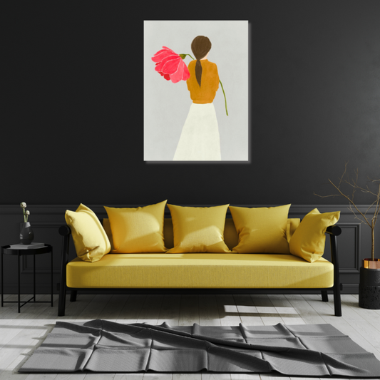 Image of a woman and ponytail from behind holding a giant poppy over her shoulder. The painting is hanging above a bright yellow couch and is set against a dark grey wall with grey waiinscotting