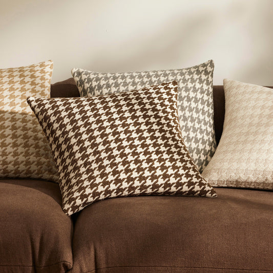 Group of houndstooth cushions in a boucle fabric resting on a brown sofa