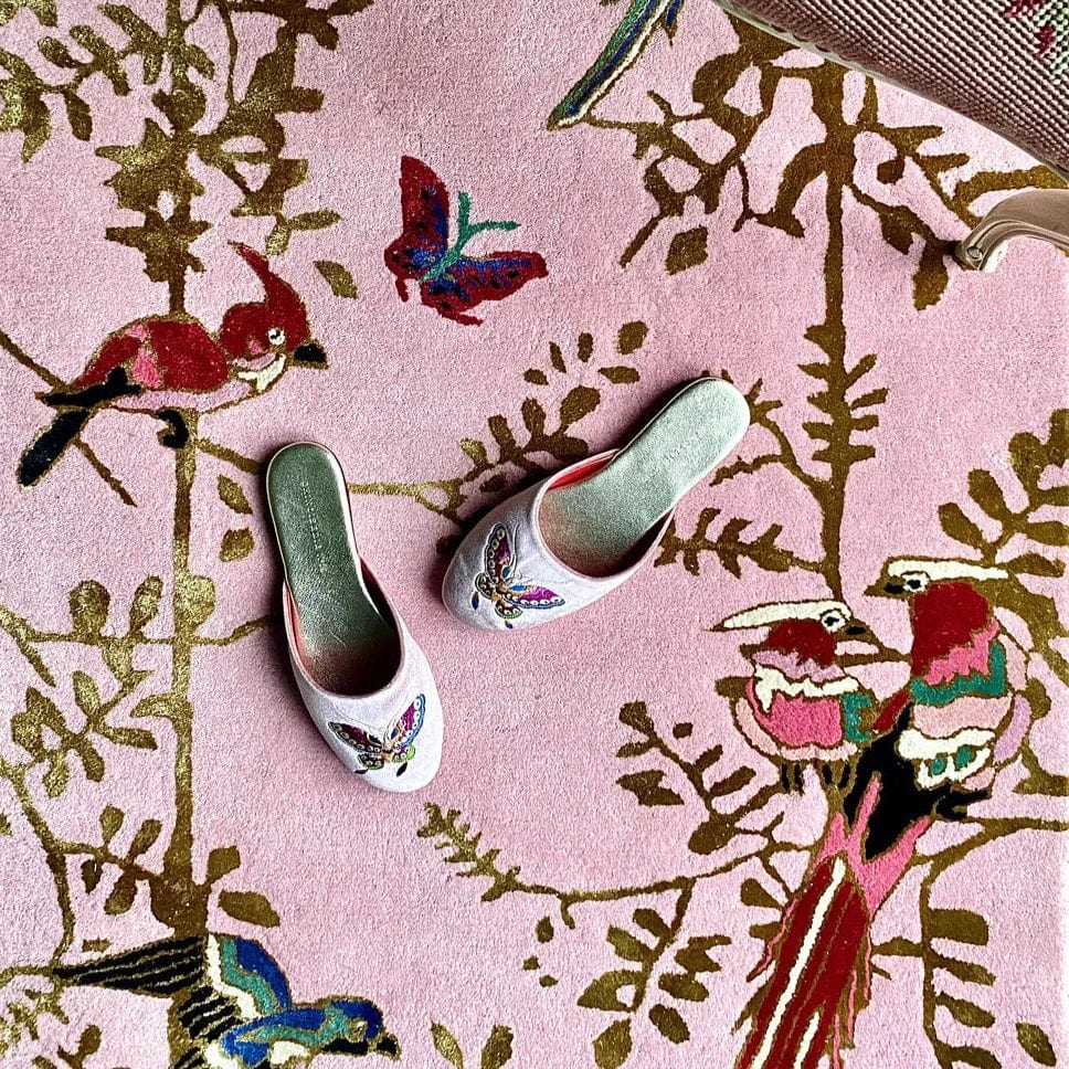 pink rug with gold floral silhouettes and tropical birds with a pair of green embroidered slippers