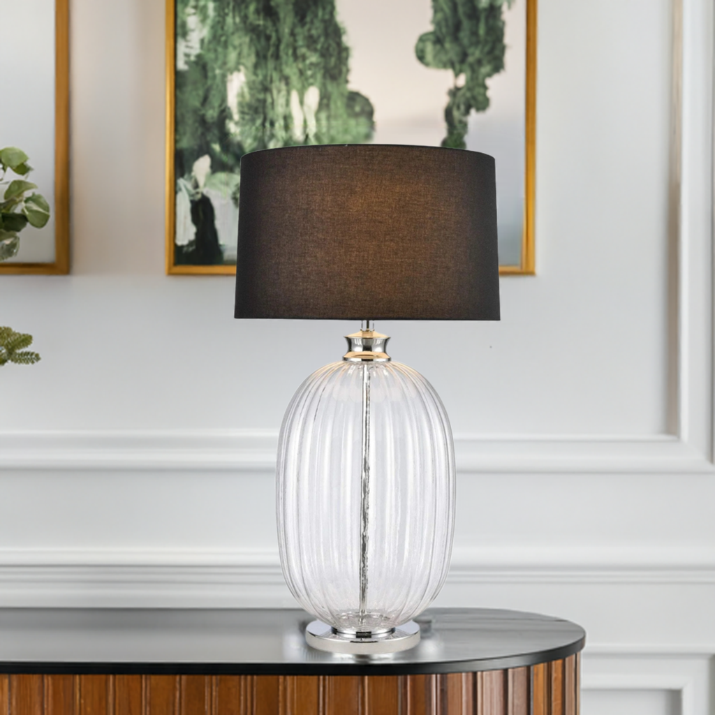 Kingsley Dawn oval glass table lamp with grove detailing and a black linen lamp shade siting on a sideboard