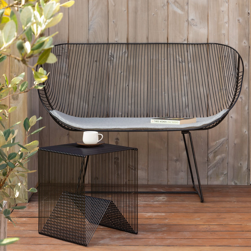 Orere wire sofa in black with a light grey cushion and a wire coffee table in front all on a wooden deck
