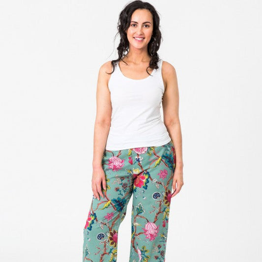 Tree of Life pattern with colourful flowers and foliage on a pale aqua background on pj pants worn by dark haired model with a white tank top