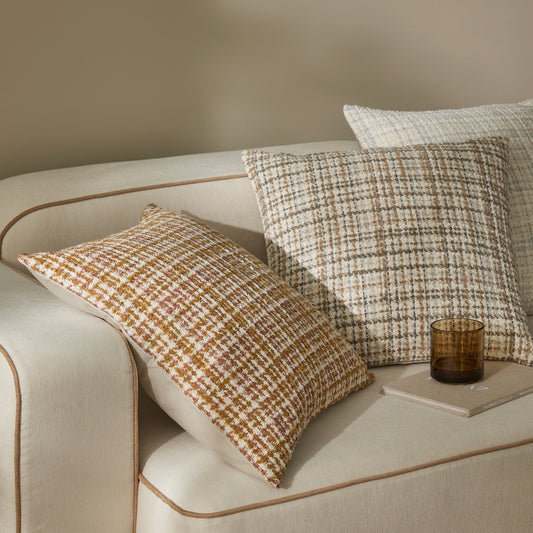 Tripoli cushion in pearl, fog and stone sitting on a cream sofa. cushions are textured with lines