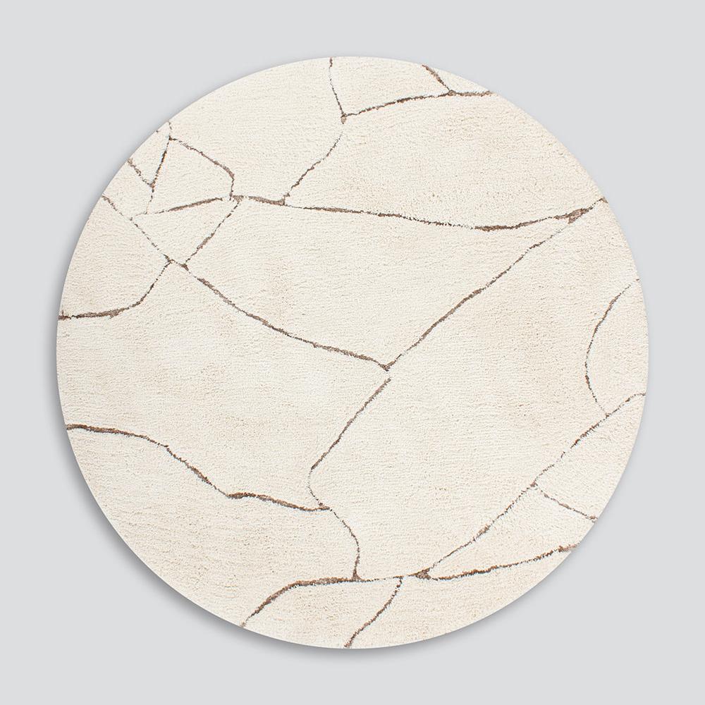 Round Aria rug in ivory with gold coloured abstract cut away lines through it
