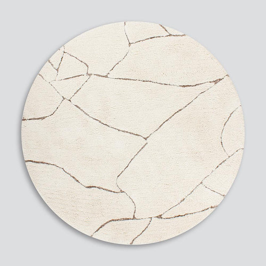 Round Aria rug in ivory with gold coloured abstract cut away lines through it
