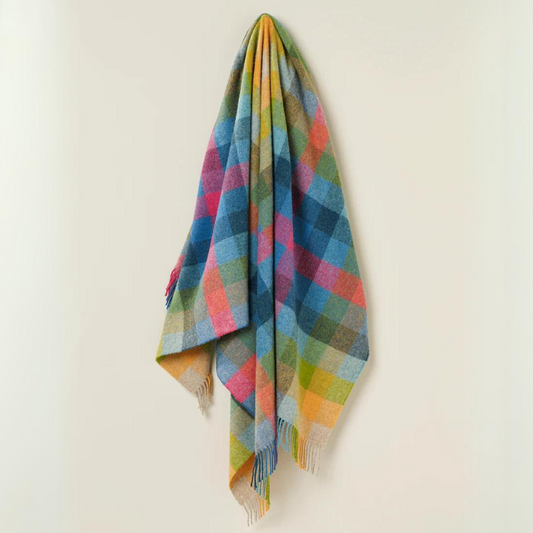 Harlequin Throw in Tutti Frutti colours of Teal, Fuchsia, Gold, Coral, and Hazel hanging up against a plain wall