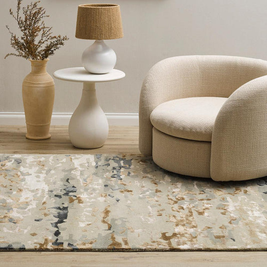 Fleur Multi Rug from Mulberi, abstract pattern of gold, greys, beignes and creams in a room scene with a sofa and vases